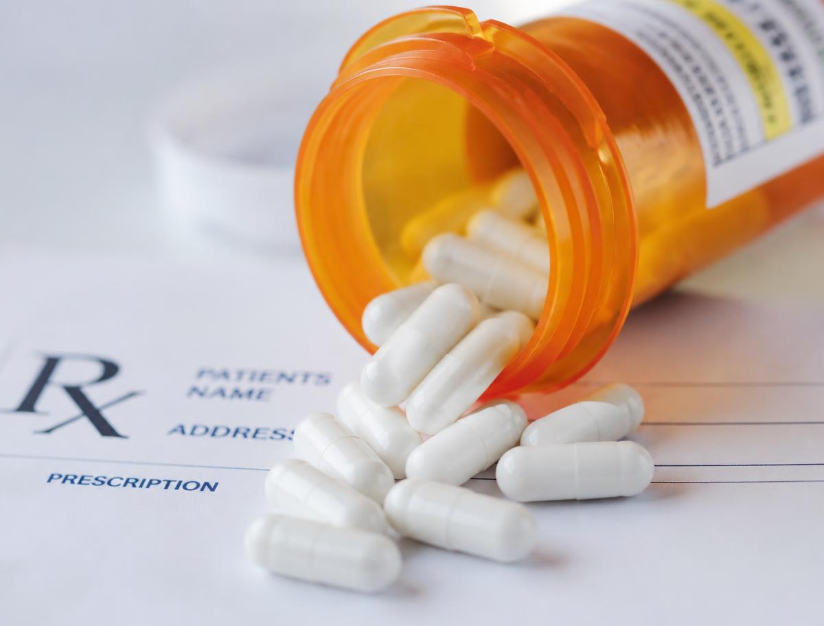 Frasco de medicamento sobre um receituário médico